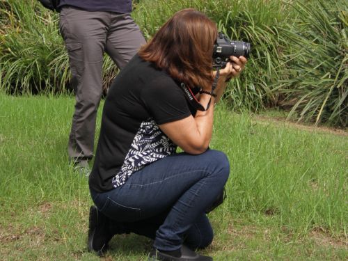 Picture of a woman kneeling and taking a photo with a camera