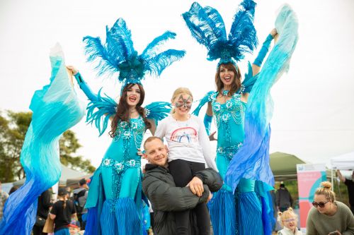 Picture of roving entertainers on stilts and with a family at Hawkesbury Fest 2024