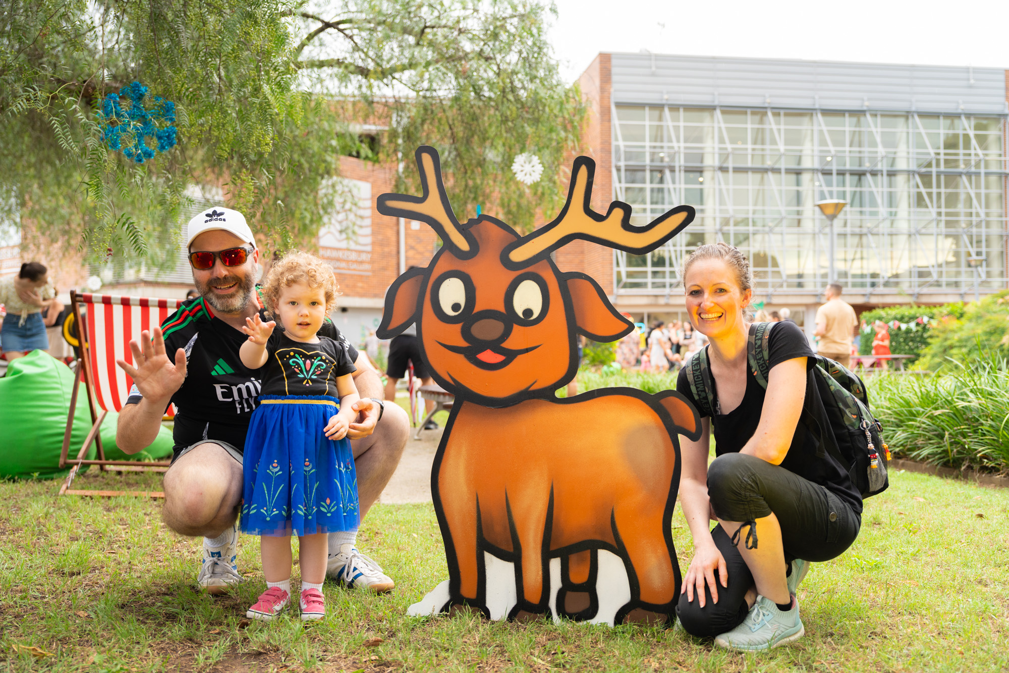 A family crouches in front of a reindeer image.