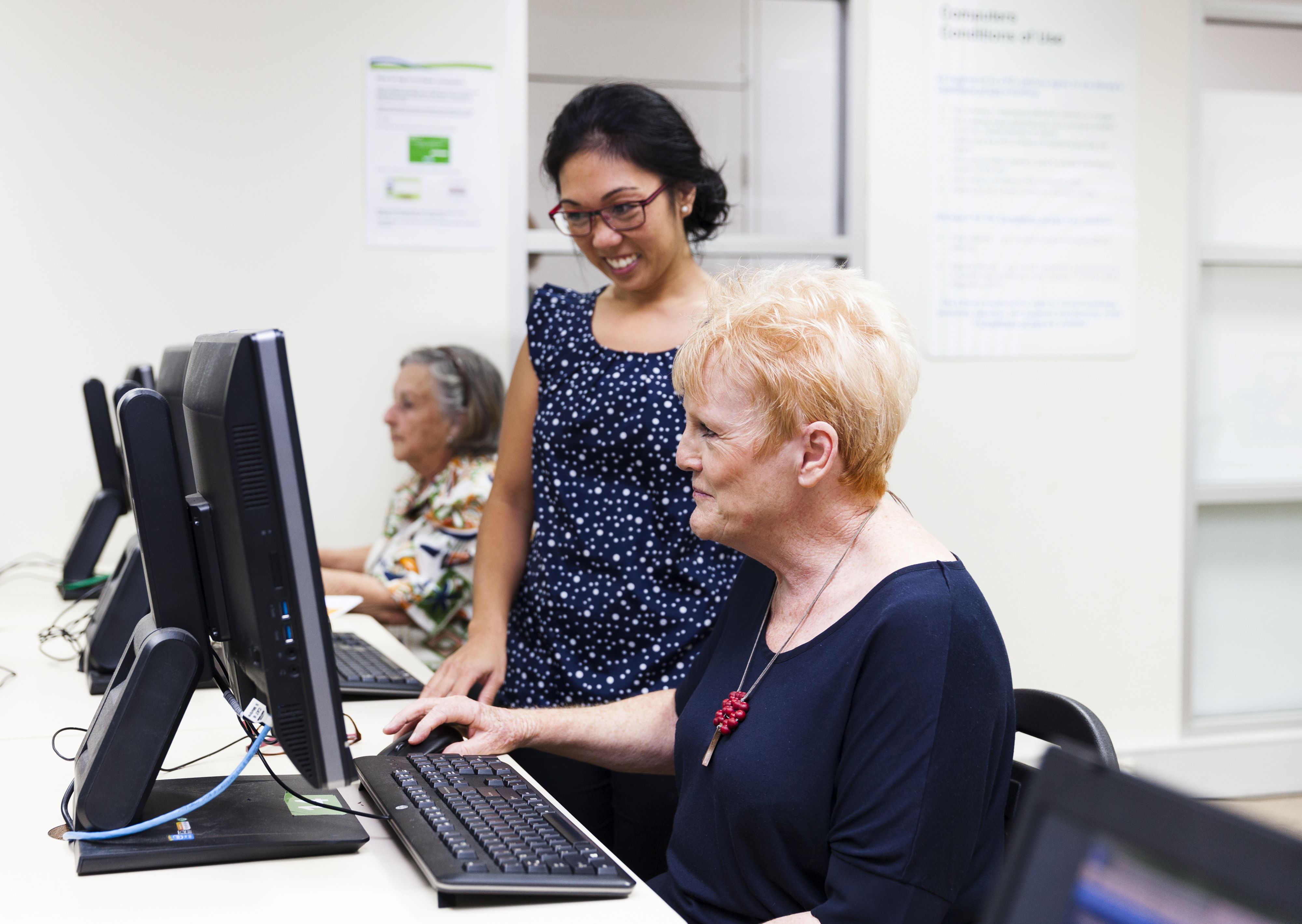 A senior is given help on a computer